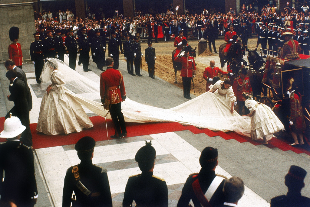 A photograph of Lady Diana Spencer arriving at St Paul's Cathedral in the City of London for her marriage to Prince Charles, Prince of Wales. Her dress and train, designed by David and Elizabeth Emmanuel is being arranged by her bridesmaids. Crowds of 60000 people lined the streets of London to watch the ceremony on 29th July 1981. Date: 29th July 1981