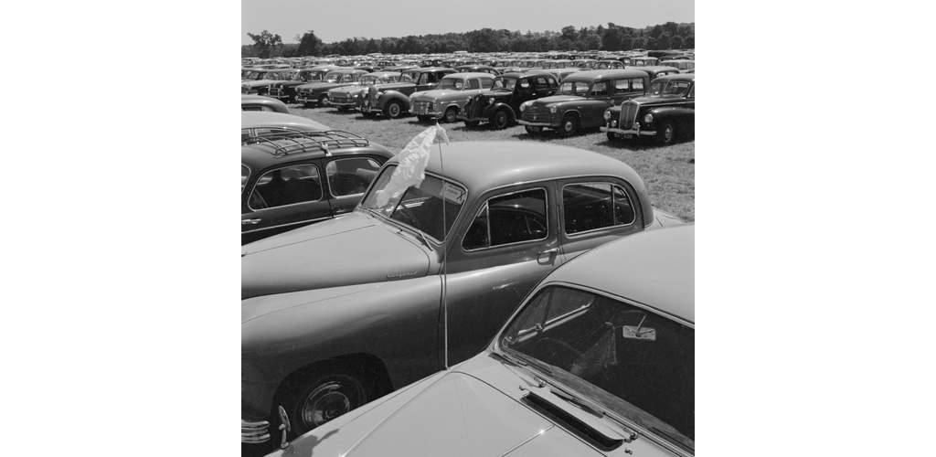 A view across the car-parking field at the Royal Show, Oxford, with a car flying a handkerchief from its radio aerial in the foreground Date: Jul 1959