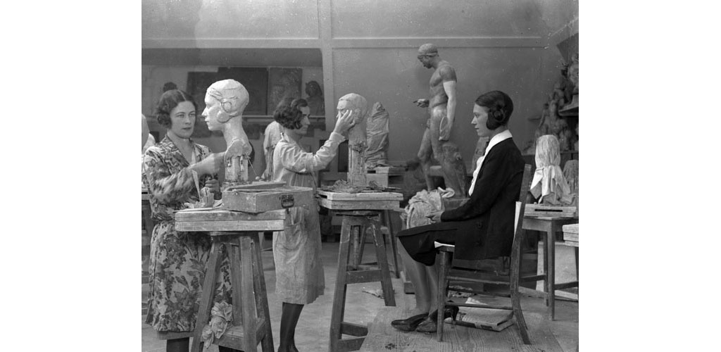 A class of female students at the London County School of Sculpture modelling clay busts based on live models. Date: 1930s