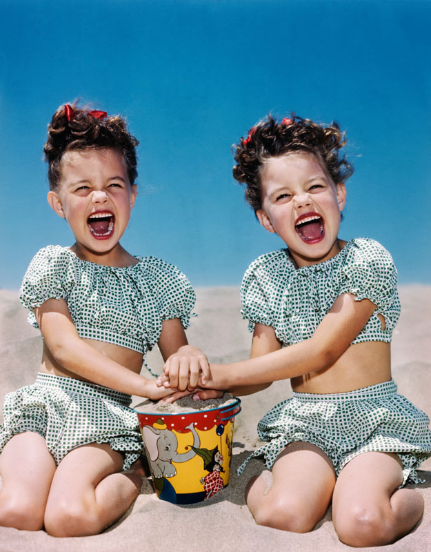 1940s 1950s SMILING LAUGHING TWIN GIRLS WEARING CHECKERED TWO PIECE BATHING SUITS PLAYING ON SANDY BEACH