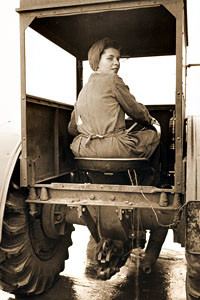 A Land Girl driving a tractor on a farm during World War II