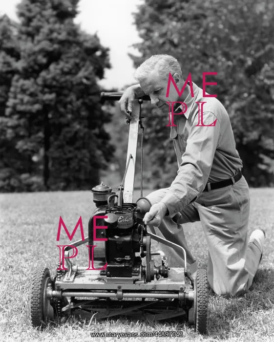  : 1940s ELDERLY MAN IN YARD KNEELING DOWN TO FIX