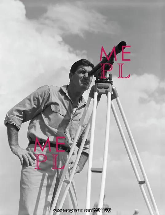 : 1960s MAN USING A THEODOLITE WHILE SURVEYING : 1960s MAN USING A THEODOLITE WHILE SURVEYING