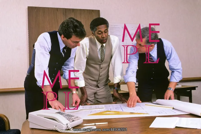 : 1980s Three Businessmen looking over Blueprints in Office : 1980s Three Businessmen looking over Blueprints in Office