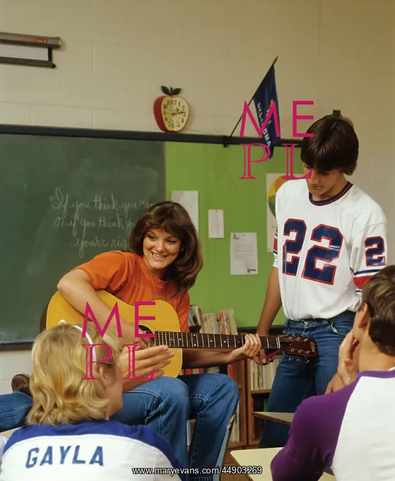  : 1980s COLLEGE STUDENTS IN CLASSROOM PLAYING GUITAR