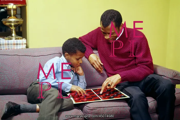 : African-American Father and Son Sitting on Couch Playing : African-American Father and Son Sitting on Couch Playing