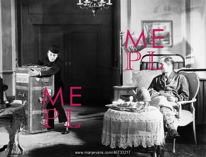 : Bellboy struggling with trunk in guests room : Bellboy struggling with trunk in guests room