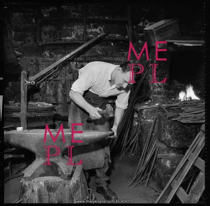 : A blacksmith working at an anvil. The location : A blacksmith working at an anvil. The location
