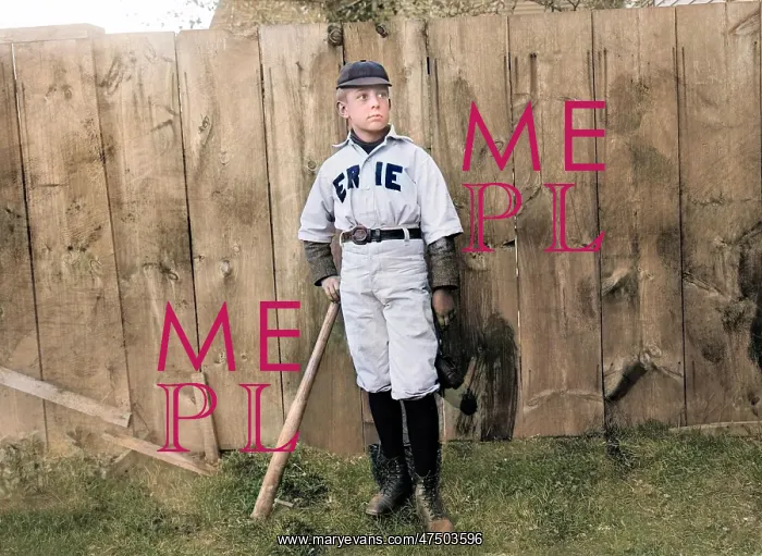  : A boy in baseball uniform by a fence in America