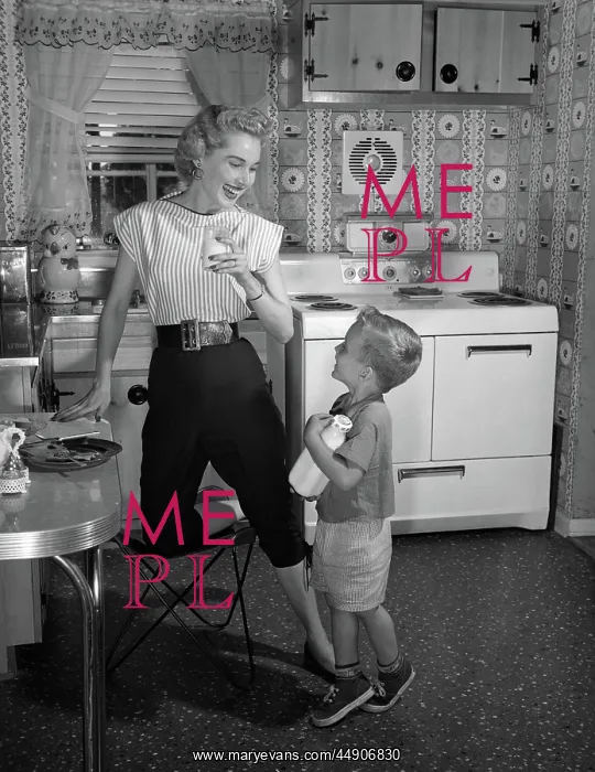 : Boy in kitchen holding bottle of milk looking : Boy in kitchen holding bottle of milk looking