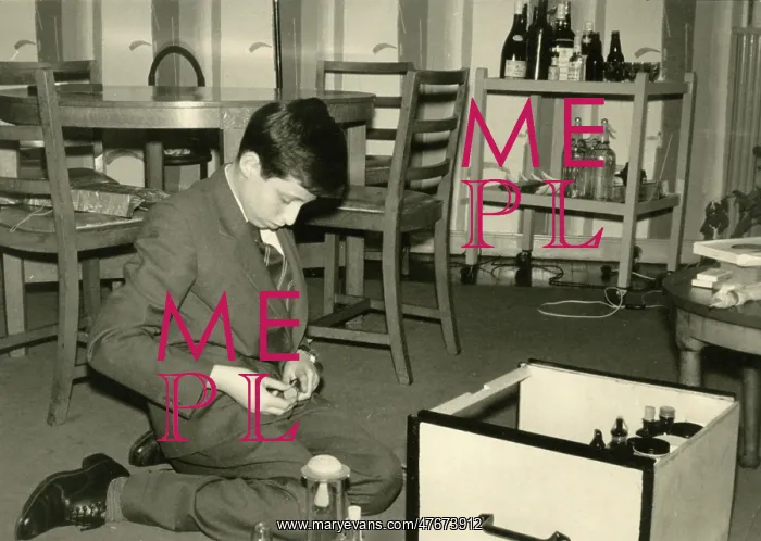: Boy kneeling on the floor sorting out some glass jars : Boy kneeling on the floor sorting out some glass jars