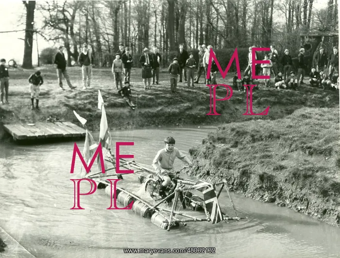 : Boy operating pedal-driven drum raft : Boy operating pedal-driven drum raft