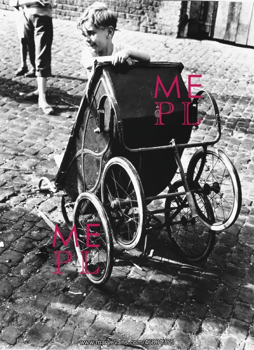 : Boy playing with pram in North Kensington : Boy playing with pram in North Kensington