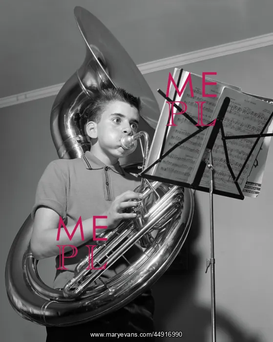 : Boy playing the tuba while reading from sheet : Boy playing the tuba while reading from sheet