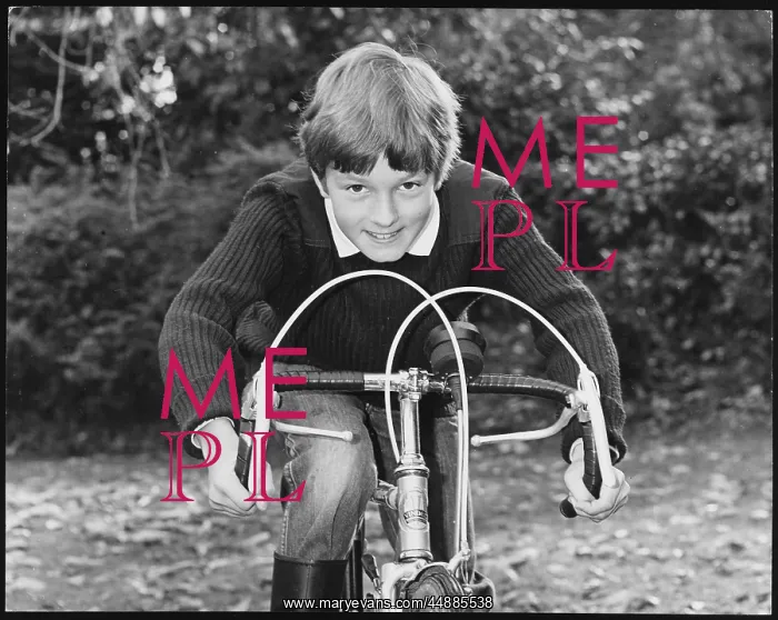  : BOY RACER. A smiling boy leaning on the handlebars of his racing bike