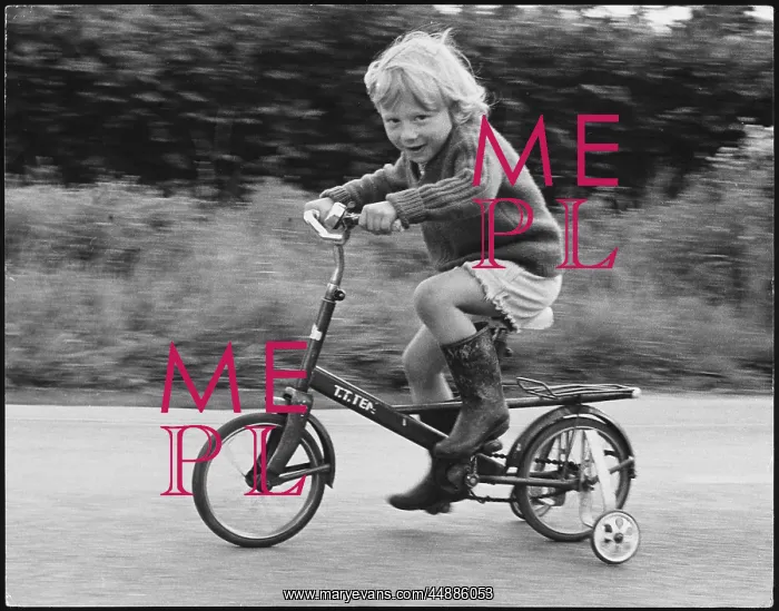 : Boy riding bicycle with stabilisers : Boy riding bicycle with stabilisers