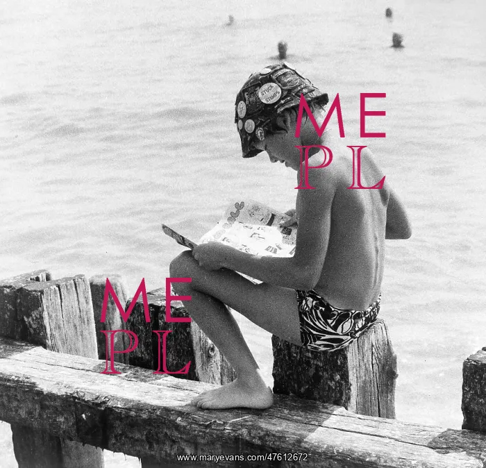 : Boy sitting on breakwater reading a comic : Boy sitting on breakwater reading a comic