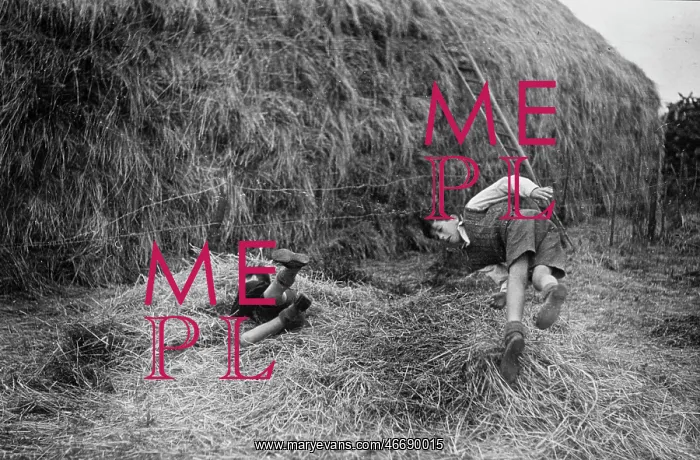 : Two boys playing near a haystack : Two boys playing near a haystack