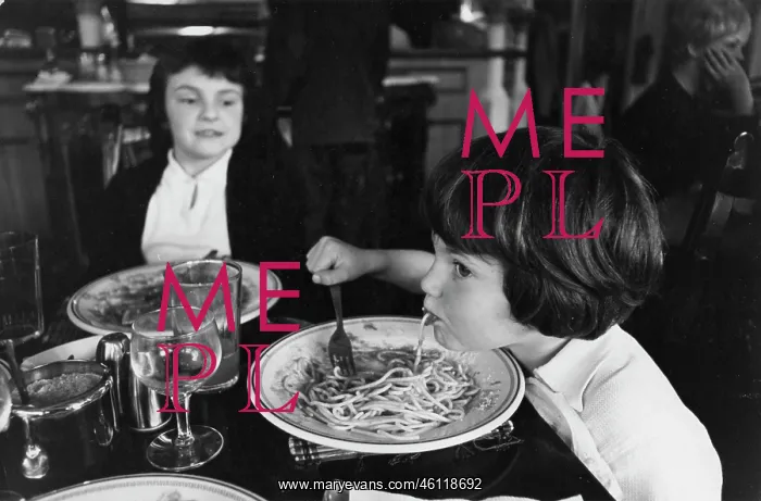 : A child eats spaghetti in a restaurant : A child eats spaghetti in a restaurant