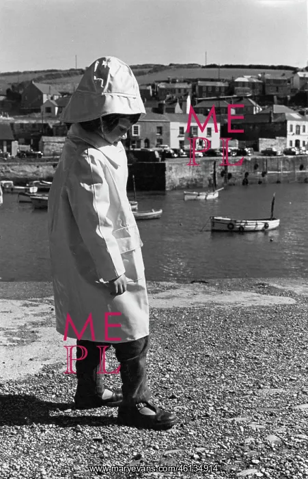 : Child in sou?wester hat and coat by a harbour : Child in sou?wester hat and coat by a harbour