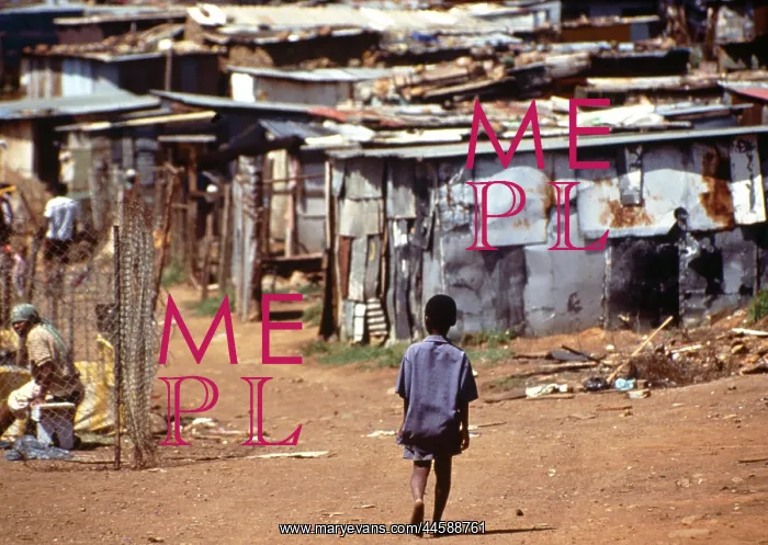 : A child walks along a dirt road towards corrugated : A child walks along a dirt road towards corrugated