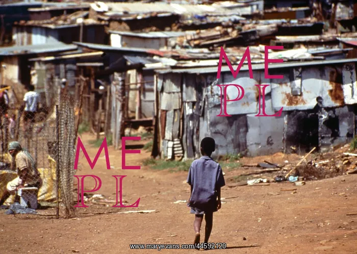 : A child walks along a dirt road towards corrugated : A child walks along a dirt road towards corrugated