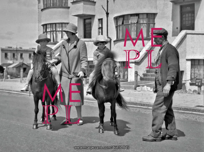 : Two children riding ponies in a street : Two children riding ponies in a street