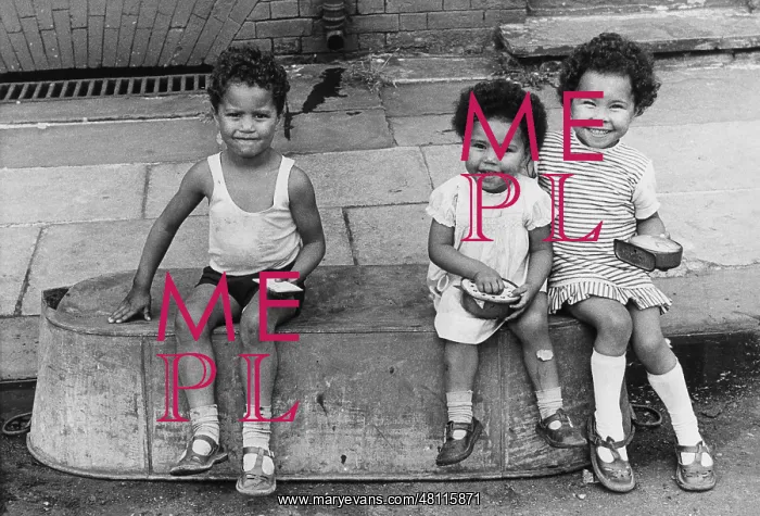: Three children sitting on an upturned tin bath : Three children sitting on an upturned tin bath