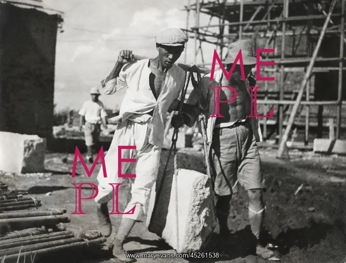 : Two Chinese men work together to life a large : Two Chinese men work together to life a large
