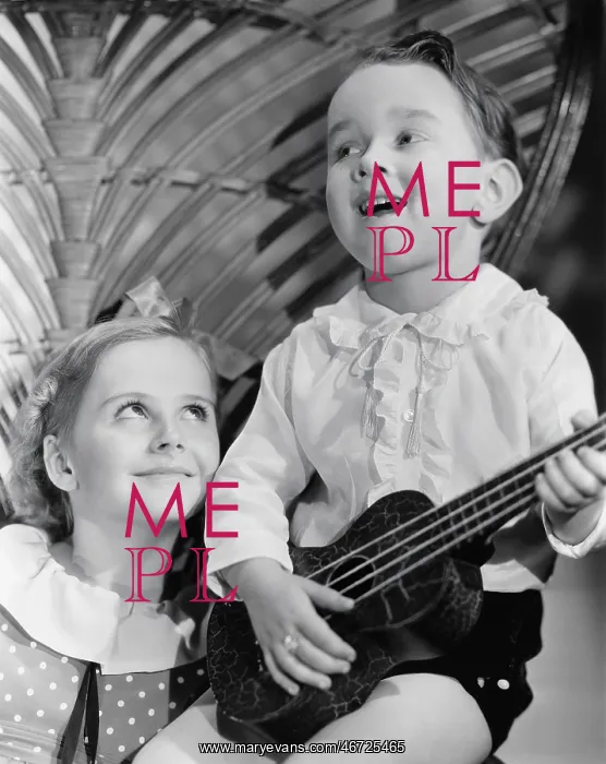 : Close-up of a boy playing a guitar with his sister : Close-up of a boy playing a guitar with his sister