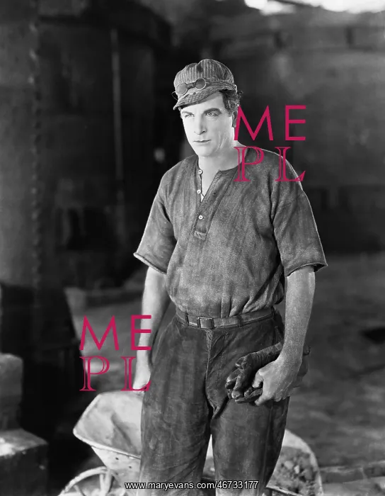 : Construction worker standing near a wheelbarrow : Construction worker standing near a wheelbarrow