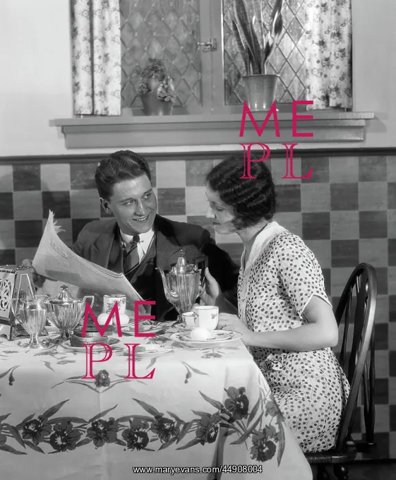 : Couple at breakfast table looking over newspaper : Couple at breakfast table looking over newspaper
