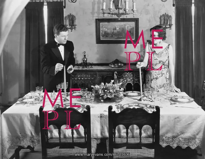 : Couple lighting candles on table set for dinner : Couple lighting candles on table set for dinner