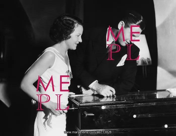 : Couple playing with pinball machine : Couple playing with pinball machine