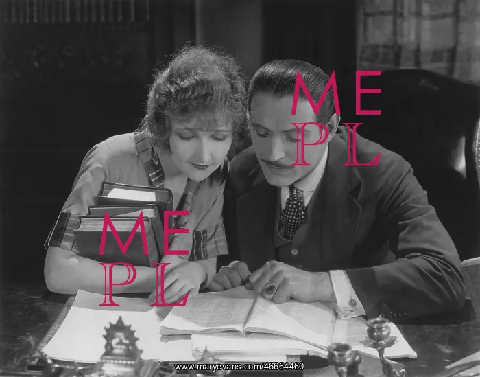 : Couple reading book at desk : Couple reading book at desk