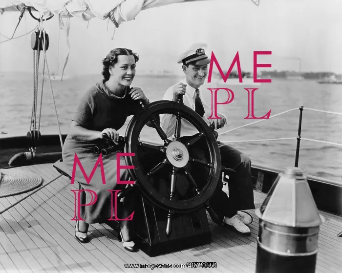 : Couple sitting on the deck of a sailboat steering the boat : Couple sitting on the deck of a sailboat steering the boat