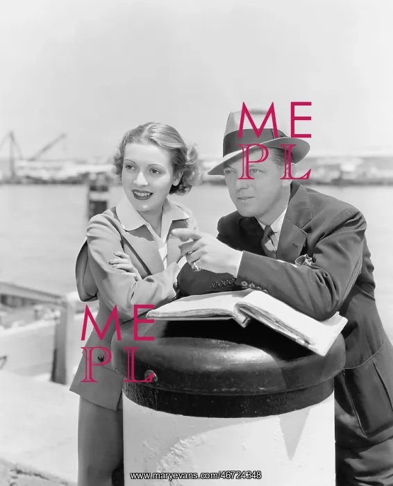 : Couple standing together looking at something in : Couple standing together looking at something in