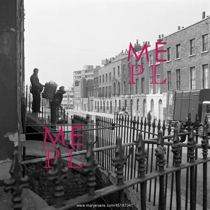 : Dustmen. A view over railings to two dustmen carrying a dustbin down the : Dustmen. A view over railings to two dustmen carrying a dustbin down the