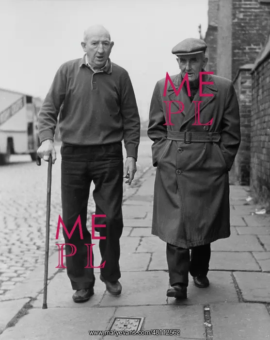 : Two elderly men walking along a pavement : Two elderly men walking along a pavement