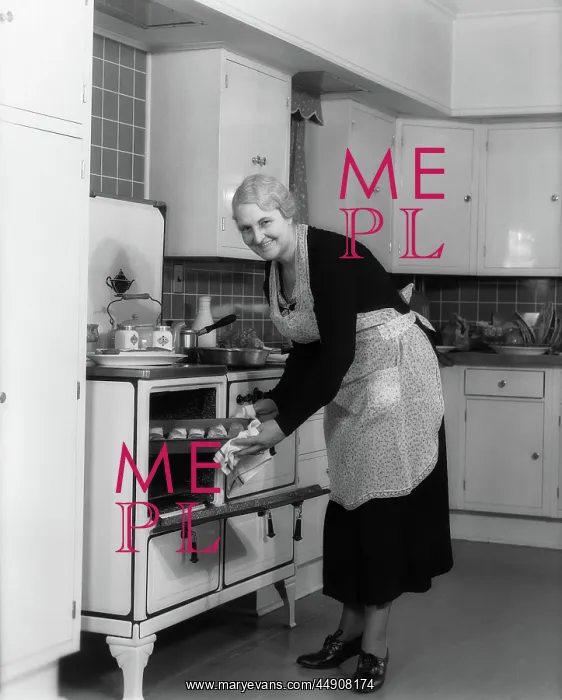  : Elderly woman taking pan of rolls out of oven