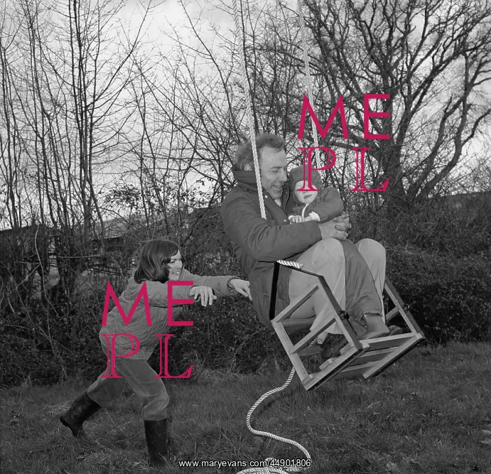 : Family in a garden playing on a swing : Family in a garden playing on a swing