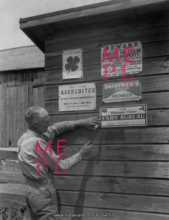 : Farmer attaches another membership sign to his : Farmer attaches another membership sign to his