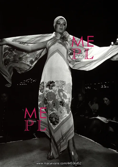 : Fashion show: a model on the cat-walk wearing a long dress with a floral : Fashion show: a model on the cat-walk wearing a long dress with a floral