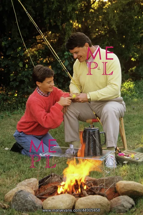 : Father and son by campfire working on fishing : Father and son by campfire working on fishing