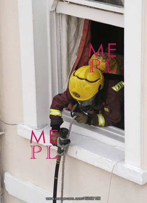 : Firefighter using a rope to pull a hose up a building : Firefighter using a rope to pull a hose up a building