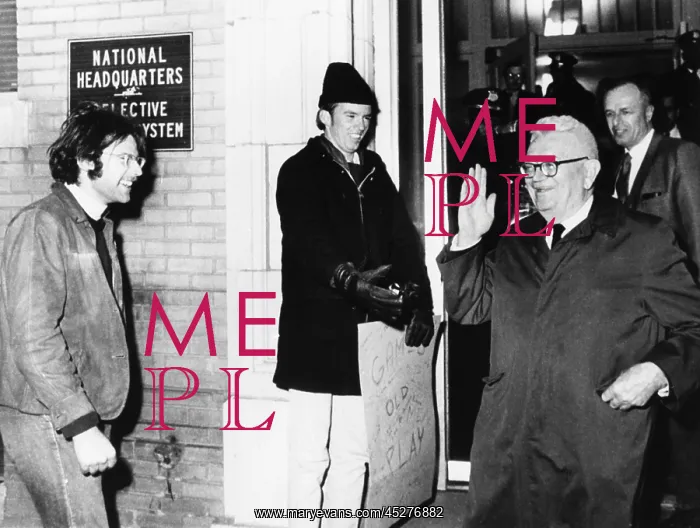 : Gen. Lewis Hershey waves to protesters outside : Gen. Lewis Hershey waves to protesters outside