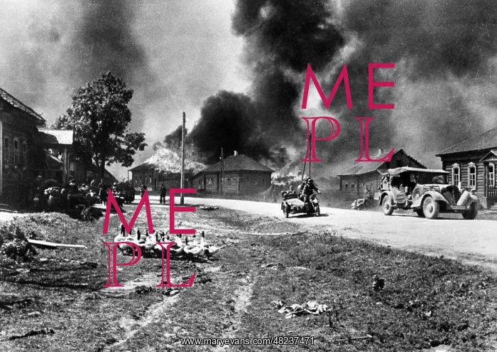 : German motorcycle troops cross a burning village on the : German motorcycle troops cross a burning village on the