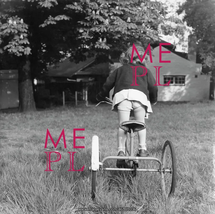 : Girl riding a tricycle through the grass : Girl riding a tricycle through the grass