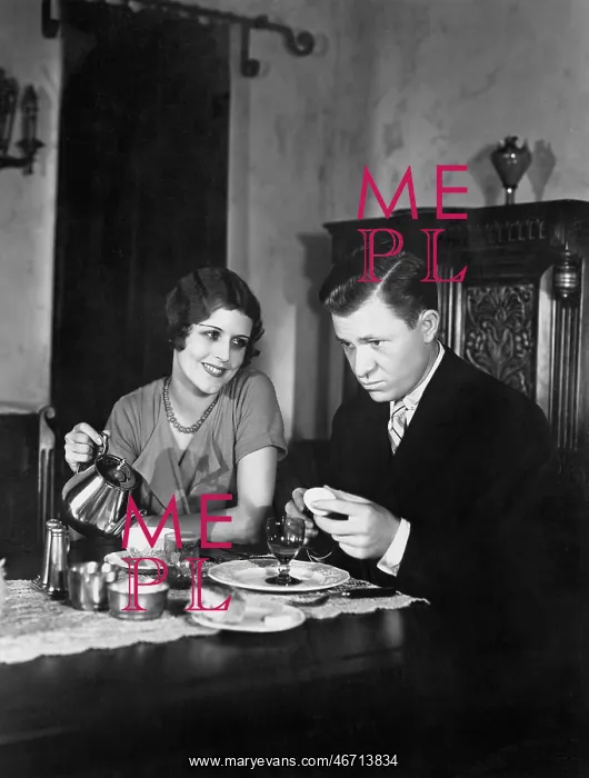: Glum man and adoring woman at breakfast table : Glum man and adoring woman at breakfast table