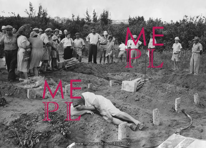 : A grief stricken mother lying on the grave of : A grief stricken mother lying on the grave of